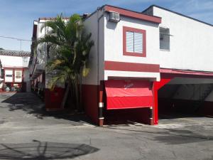 a red and white building with a palm tree next to it at Motel Sedução in Sao Paulo