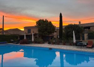 a swimming pool in front of a house with a sunset at Gîte de la Garriguette in Rasteau