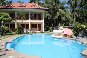 a swimming pool in front of a house at Wellbeach Dive Resort in Zamboanguita