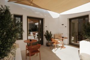 a patio with two tables and chairs and windows at The Lofts Paros Executive Suites in Naousa