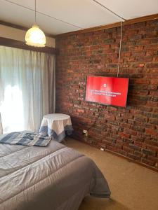 a bedroom with a brick wall and a tv on a wall at Halkett Corner in Kimberley