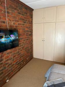 a bedroom with a brick wall with a tv on it at Halkett Corner in Kimberley