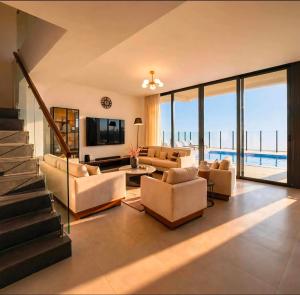 a living room with a couch and chairs and a television at Ajmal Villa in Al Ḩamrīyah