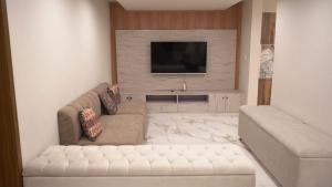 a living room with a couch and a flat screen tv at The Bliss avenue in Murree