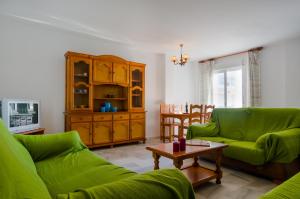 una sala de estar con 2 sofás verdes y una mesa. en Apartamentos Carril de la Fuente, en Conil de la Frontera