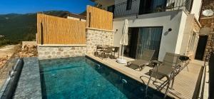 a swimming pool with chairs and a house at Aera Villas - Kaş in Kaş