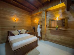 a bedroom with a bed in a room with wooden walls at Lava Ella in Ella