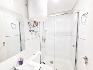 a white bathroom with a shower and a sink at Hospedaje La Campana in Madrid