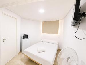 a white room with a white bench and a tv at Hospedaje La Campana in Madrid