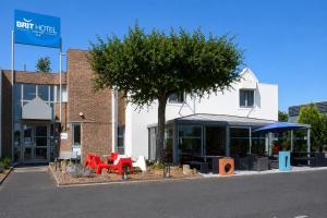 a building with tables and a tree in front of it at BRIT HOTEL Caen Hérouville in Hérouville-Saint-Clair