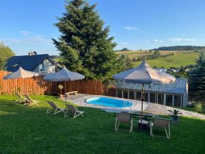 a backyard with a pool and chairs and umbrellas at Chyże na Zbyrze in Mochnaczka Niżna