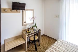 a bedroom with a desk with a chair and a bed at Hotel Christian in Lido di Jesolo