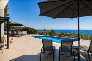 a patio with chairs and an umbrella and a swimming pool at Blue Infinity Villa 33 in Neo Chorio