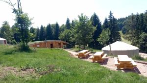 a group of picnic tables and a yurt in a field at La Yourte Un Autre Monde in Le Hohwald