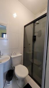 a bathroom with a toilet and a shower and a sink at Pousada Nova Onda in Paranaguá