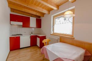 a small kitchen with red cabinets and a window at B&B Apartments La Palsa in San Cassiano
