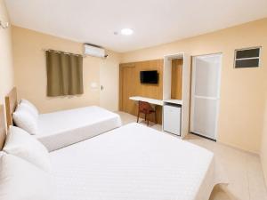 a hotel room with two beds and a desk at Pousada Milagres in Canindé