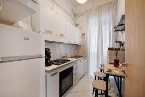 a white kitchen with a stove and a refrigerator at Home Joséphine - Caserta in Caserta