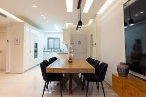 a dining room with a wooden table and black chairs at שאנל דירת גן עם בריכה in Eilat