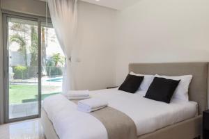 a white bed with black pillows in a room with a window at שאנל דירת גן עם בריכה in Eilat +54 photos