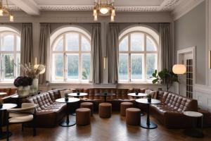 a large room with couches and tables and windows at Hotel GRACE LA MARGNA ST MORITZ in St. Moritz