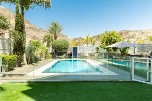 a swimming pool in the middle of a yard with palm trees at שאנל דירת גן עם בריכה in Eilat