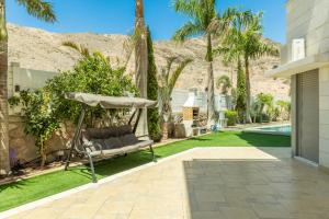 a backyard with a hammock and palm trees at שאנל דירת גן עם בריכה in Eilat