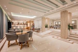 a lobby with chairs and tables and a piano at Hotel Palmyra in Argassi