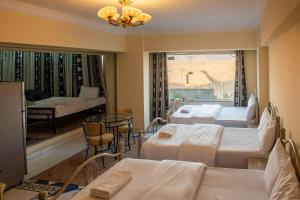 a room with three beds and a table and a window at Pyramita luxury hotel in ‘Ezbet `Abd el-Ḥamîd