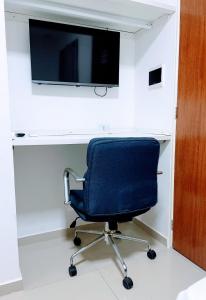 a desk with a chair and a television on a wall at Princesa do Sertão Pousada in Palmeira dos Índios