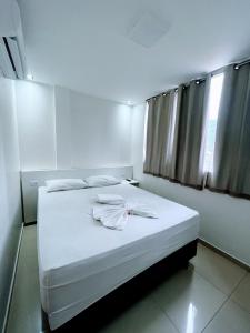 a bedroom with a bed with white sheets and pillows at Princesa do Sertão Pousada in Palmeira dos Índios