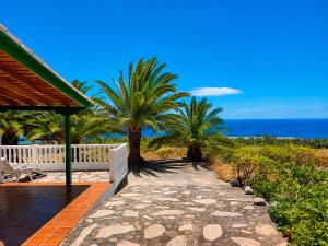 a porch with a bench and palm trees and the ocean at Pancho Molina in Puntallana