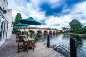 Eine Holzterrasse mit Tischen und Sonnenschirmen neben einem Fluss in der Unterkunft Thames Riviera Hotel, Sure Hotel Collection by Best Western in Maidenhead + 38 Fotos