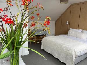 a bedroom with a bed and a vase with red flowers at Leac na Cille in Dingle