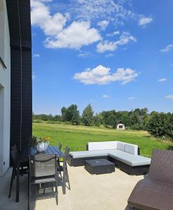 a patio with a couch and a table and chairs at Królowa Beskidu in Słopnice