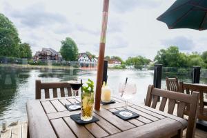 ein Holztisch mit Weingläsern und einem Sonnenschirm in der Unterkunft Thames Riviera Hotel, Sure Hotel Collection by Best Western in Maidenhead