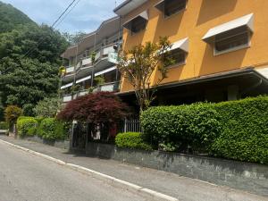 a yellow building with a fence and bushes next to a street at Albergo Milena in Gardone Val Trompia
