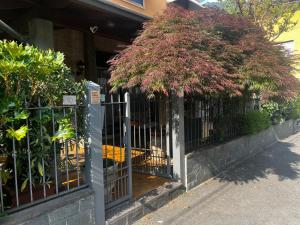 a fence with a tree in front of a building at Albergo Milena in Gardone Val Trompia