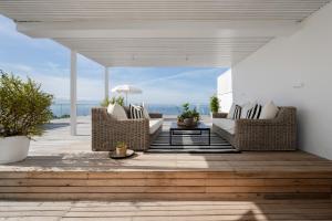 eine Terrasse mit Korbstühlen und einem Tisch auf einem Deck in der Unterkunft Eleven in Plettenberg Bay