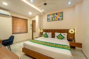 a bedroom with a large bed with a desk and a chair at Treebo Golden Palm, Civil Lines in Jabalpur +26 photos