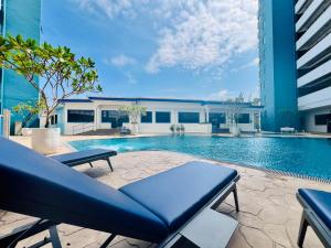 a swimming pool with a blue couch and a building at Mutiara Melaka Beach Resort Condominium,Pantai Puteri Melaka in Malacca