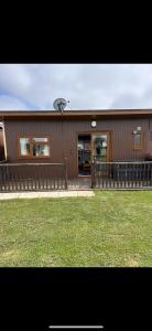 a brown house with a fence and a yard at 2 Bedroom cosy chalet Mablethorpe in Mablethorpe