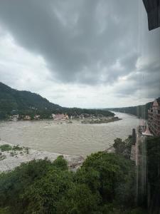 a view of a river with trees and buildings at Om Guesthouse in Rishīkesh