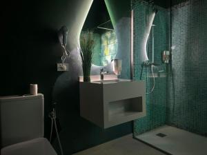 a bathroom with a sink and a shower with green tiles at Hotel Zouk Suite Spa in Alba Iulia