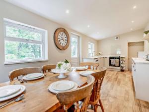 a dining room with a table and chairs and a clock on the wall at Upper Hillside Cottage in Blairgowrie