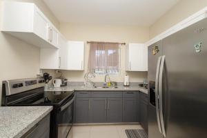 a kitchen with white cabinets and a stainless steel refrigerator at Oceanpointe Luxury Retreat in Georgia