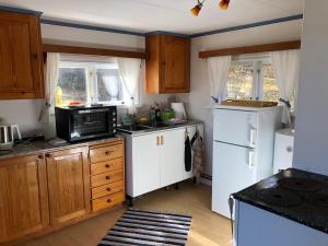 a kitchen with wooden cabinets and a white refrigerator at Waldhaus mit Seeblick in Nyhammar