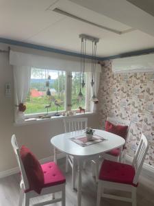 a kitchen with a white table and chairs and a window at Waldhaus mit Seeblick in Nyhammar +16 photos