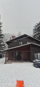 a snow covered house with a car parked in front of it at Cabana Elena in Rausor