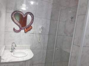 a bathroom with a shower with a sink and a heart mirror at Motel Sedução in São Paulo